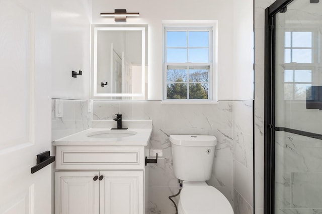 bathroom featuring toilet, vanity, tile walls, and a shower with shower door