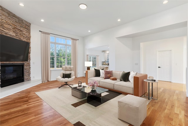 living room featuring a stone fireplace and light hardwood / wood-style floors