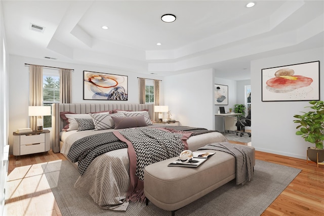 bedroom with a raised ceiling and light hardwood / wood-style flooring