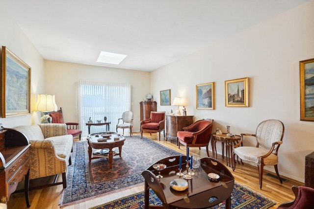 living room with a skylight and light hardwood / wood-style floors