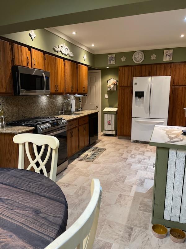 kitchen featuring appliances with stainless steel finishes, sink, crown molding, and tasteful backsplash