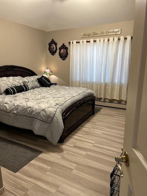 bedroom featuring a baseboard radiator and light hardwood / wood-style flooring