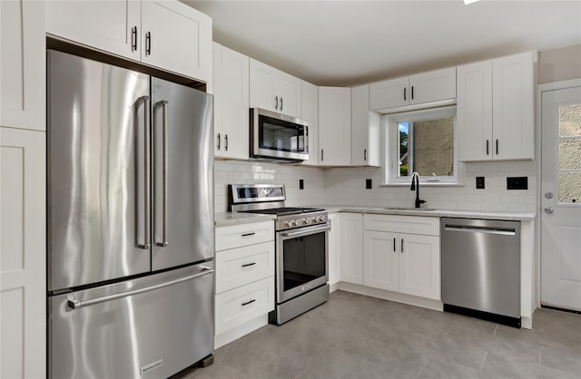 kitchen featuring white cabinetry, sink, light stone countertops, decorative backsplash, and appliances with stainless steel finishes