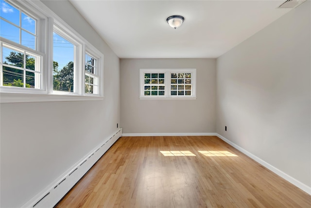 empty room with light wood-type flooring and a baseboard heating unit