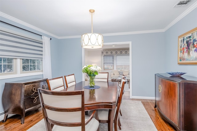 dining area with light hardwood / wood-style flooring and ornamental molding