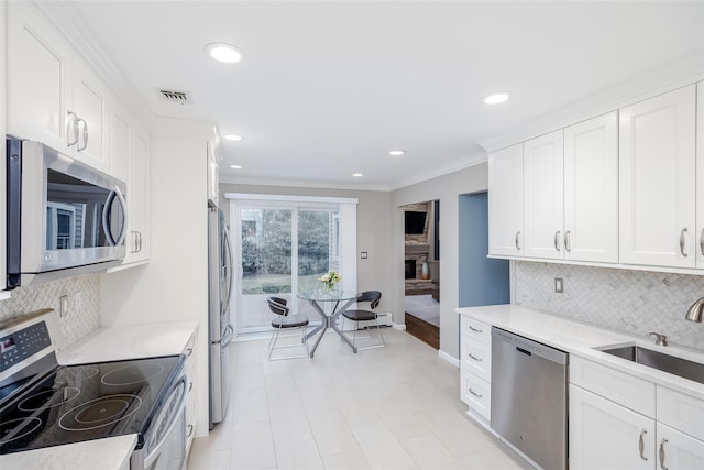 kitchen featuring decorative backsplash, sink, crown molding, white cabinetry, and appliances with stainless steel finishes