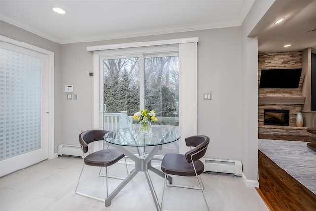 dining space with baseboard heating, a large fireplace, and crown molding