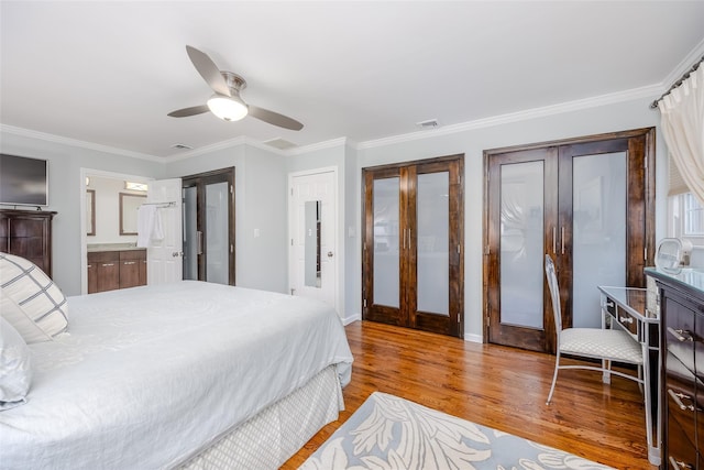 bedroom with light wood-type flooring, ceiling fan, crown molding, and multiple closets