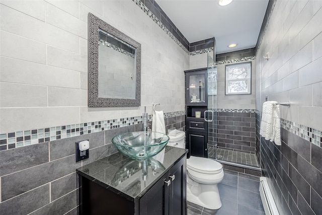 bathroom with toilet, vanity, tile walls, tiled shower, and baseboard heating