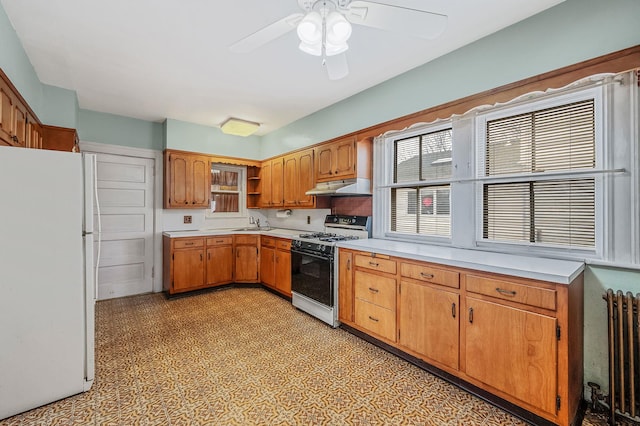 kitchen featuring white appliances, radiator heating unit, and ceiling fan