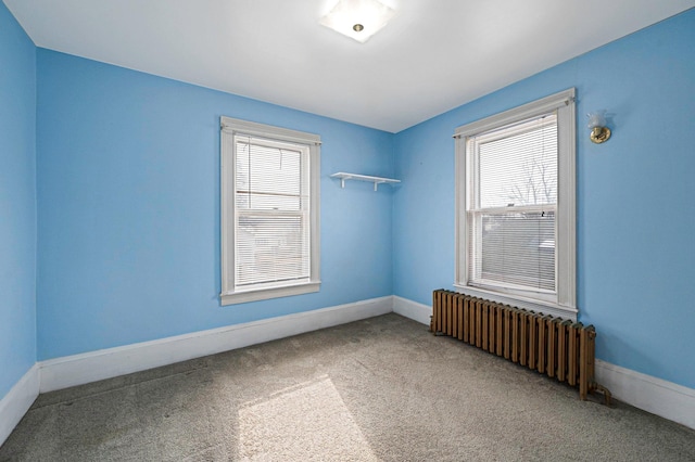 carpeted spare room featuring radiator heating unit and plenty of natural light