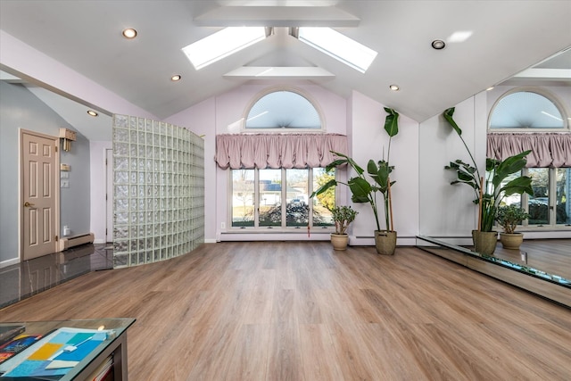 exercise area with hardwood / wood-style floors, baseboard heating, and lofted ceiling with skylight