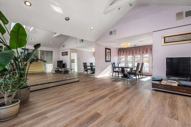 living room featuring baseboard heating, an inviting chandelier, high vaulted ceiling, and wood-type flooring