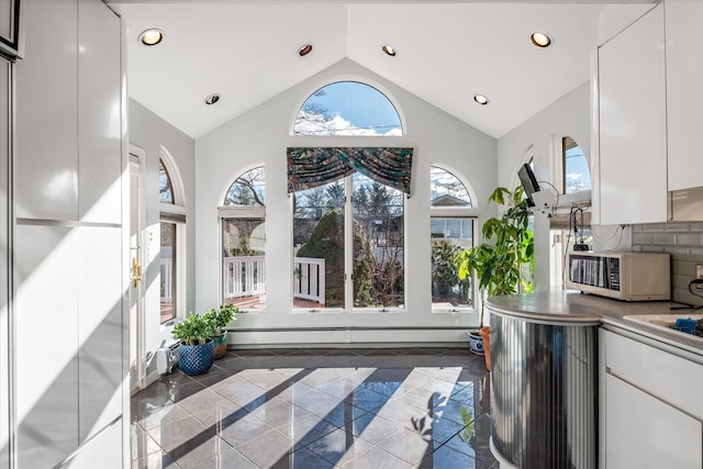 kitchen with decorative backsplash, white cabinetry, a baseboard radiator, and a wealth of natural light