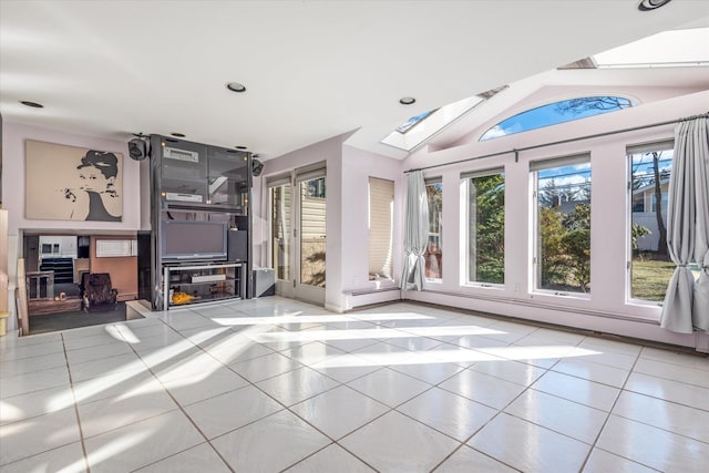 interior space with tile patterned flooring, a baseboard heating unit, a healthy amount of sunlight, and vaulted ceiling with skylight