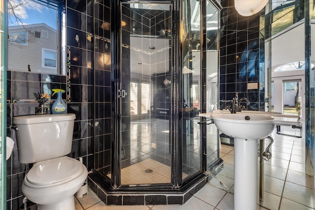 bathroom featuring toilet, a shower with door, tile walls, and tile patterned floors