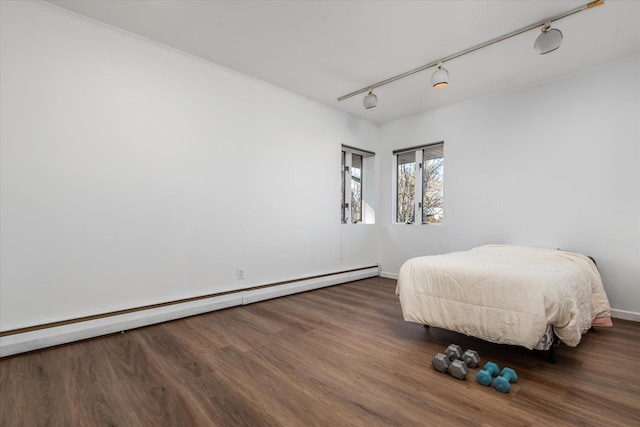 bedroom with track lighting, a baseboard heating unit, and dark wood-type flooring