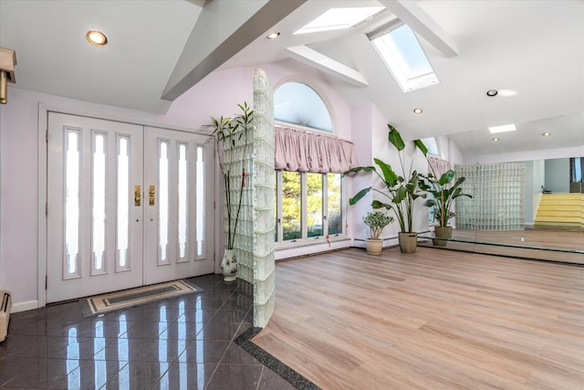 entryway featuring a skylight and high vaulted ceiling