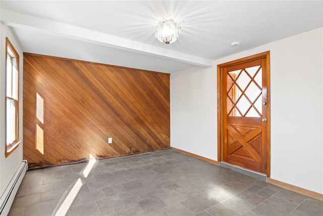 spare room featuring a baseboard heating unit and wooden walls