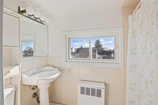 bathroom featuring radiator heating unit, toilet, a shower with shower curtain, and tile walls