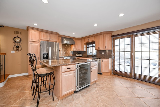 kitchen featuring a center island, light stone countertops, wall chimney range hood, stainless steel appliances, and wine cooler