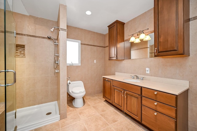 bathroom with tile walls, toilet, vanity, and an enclosed shower