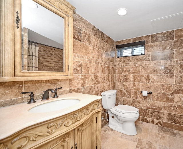 bathroom with vanity, toilet, and tile walls