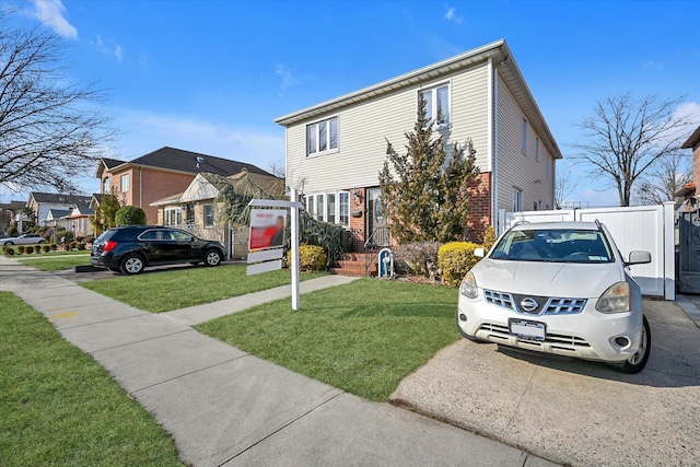 view of front of house with a front yard, a residential view, fence, and brick siding