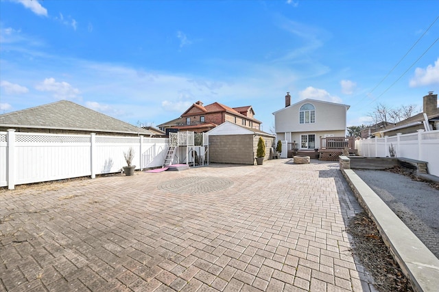 view of front of house featuring a patio area, a fenced backyard, an outdoor structure, and a deck