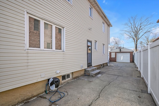 view of property exterior with an outbuilding, entry steps, a detached garage, fence, and driveway