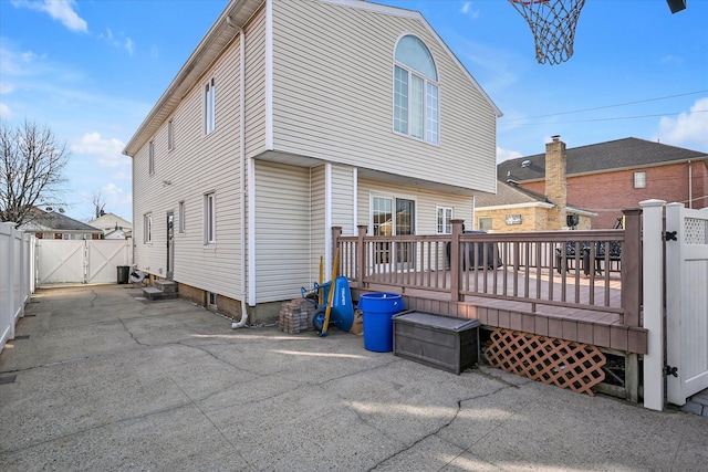 rear view of property with a gate, fence, and a deck