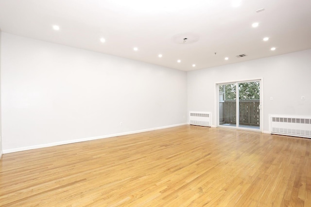 empty room featuring radiator and light hardwood / wood-style flooring