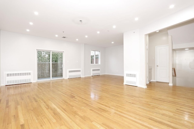 unfurnished living room with radiator and light hardwood / wood-style flooring