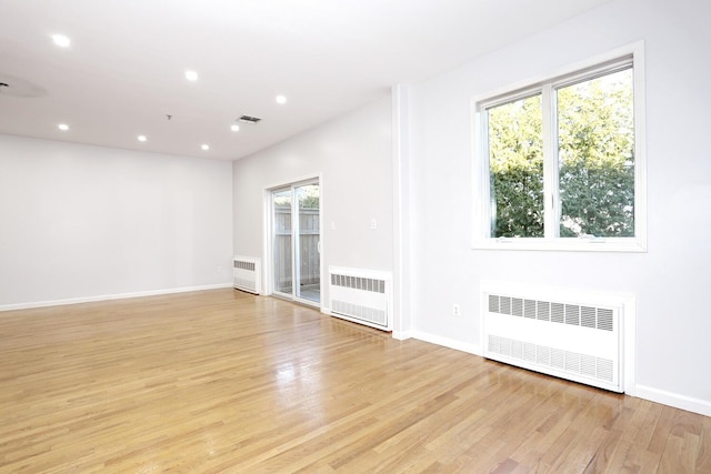 unfurnished living room featuring radiator and light wood-type flooring