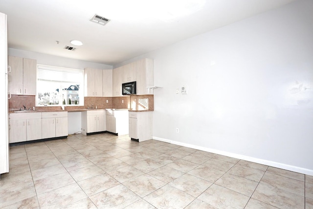 kitchen with sink, light tile patterned flooring, and backsplash