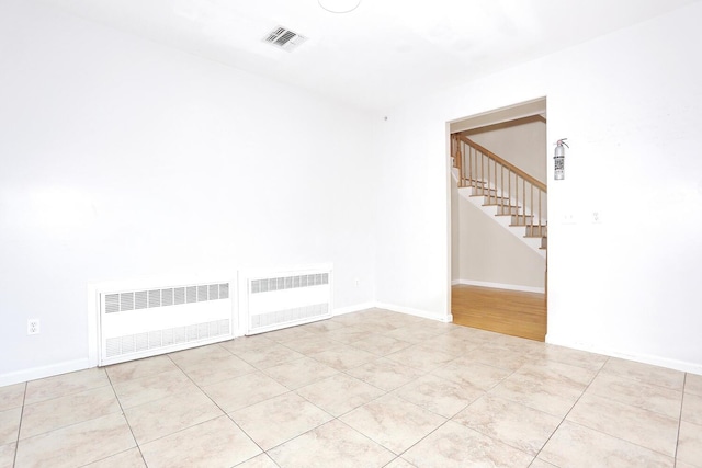 tiled empty room featuring radiator heating unit