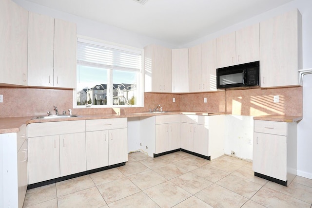 kitchen featuring light tile patterned floors, backsplash, and sink