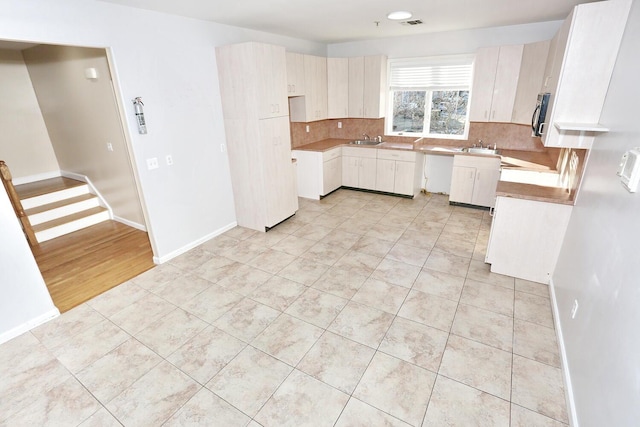 kitchen featuring sink, light tile patterned flooring, and tasteful backsplash