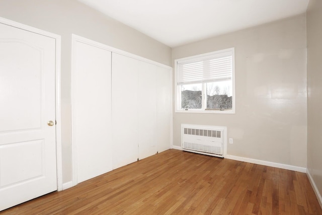 unfurnished bedroom with hardwood / wood-style floors and radiator