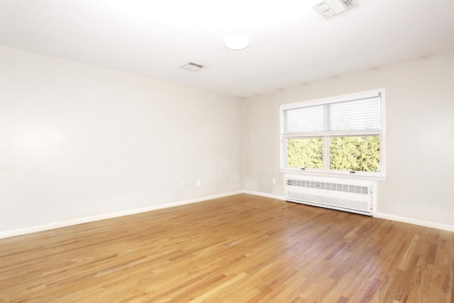 spare room featuring light hardwood / wood-style flooring and radiator