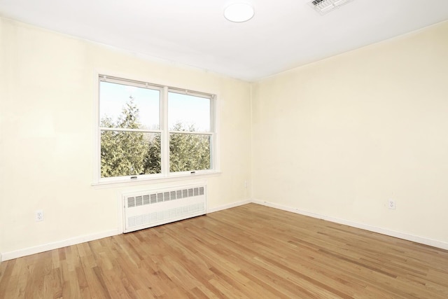 unfurnished room featuring light hardwood / wood-style floors and radiator heating unit