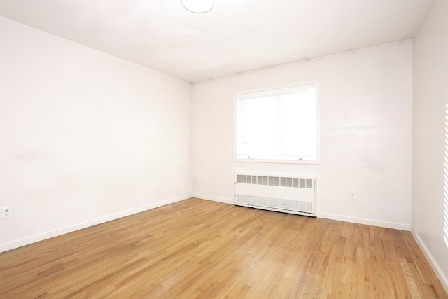 empty room featuring radiator heating unit and light hardwood / wood-style flooring