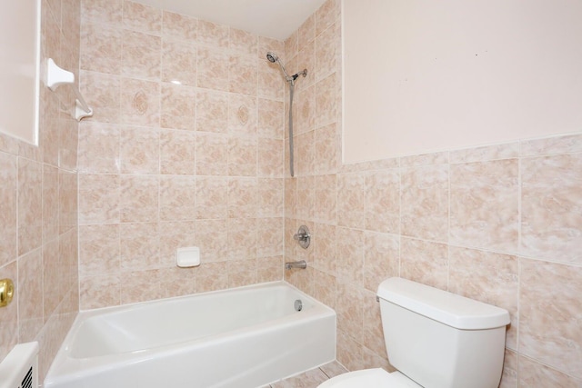 bathroom featuring toilet, tile walls, and tiled shower / bath combo