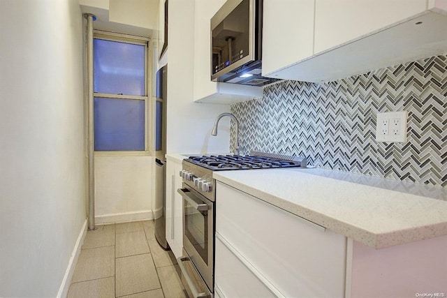 kitchen with white cabinets, stainless steel appliances, backsplash, and light tile patterned floors