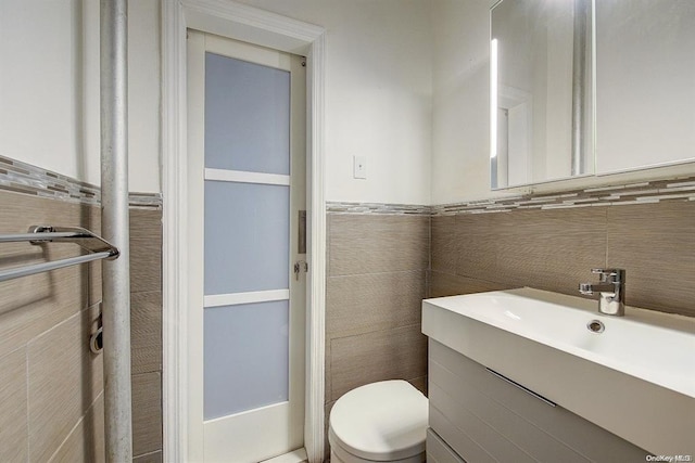 bathroom with tile walls, toilet, and vanity