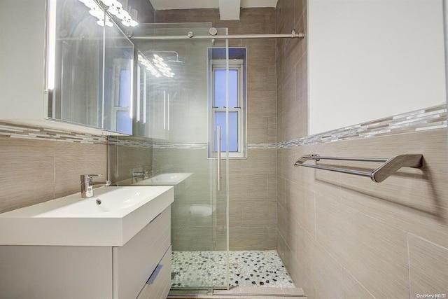 bathroom with tile walls, a shower with shower door, and vanity