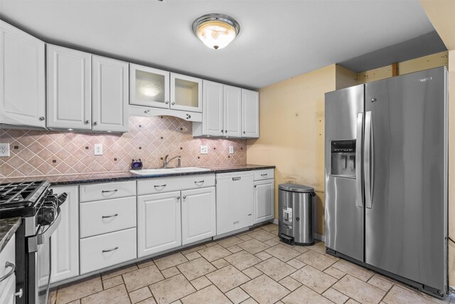 kitchen featuring backsplash, dark stone countertops, sink, appliances with stainless steel finishes, and white cabinets