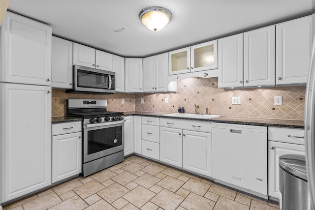 kitchen featuring sink, dark stone countertops, stainless steel appliances, and white cabinetry