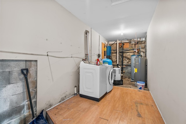 clothes washing area with water heater, light hardwood / wood-style flooring, and washing machine and dryer