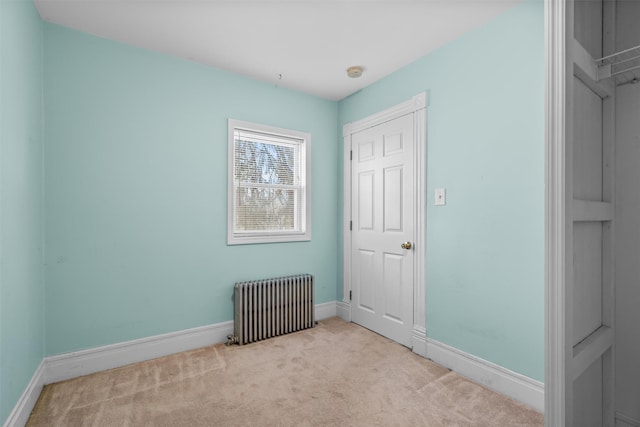 spare room featuring radiator and light carpet